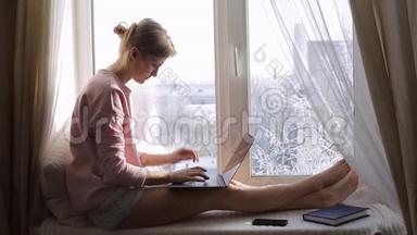 伤心难过的女人用笔记本电脑坐在窗台上